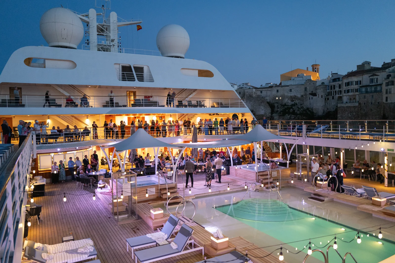Evening sailaway deck party on Seabourn Sojourn docked in Mahon, Spain at dusk